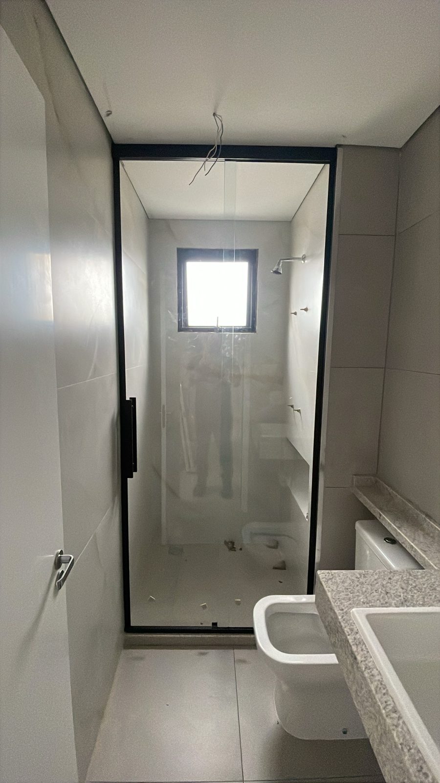 Box de vidro transparente com puxador preto em banheiro