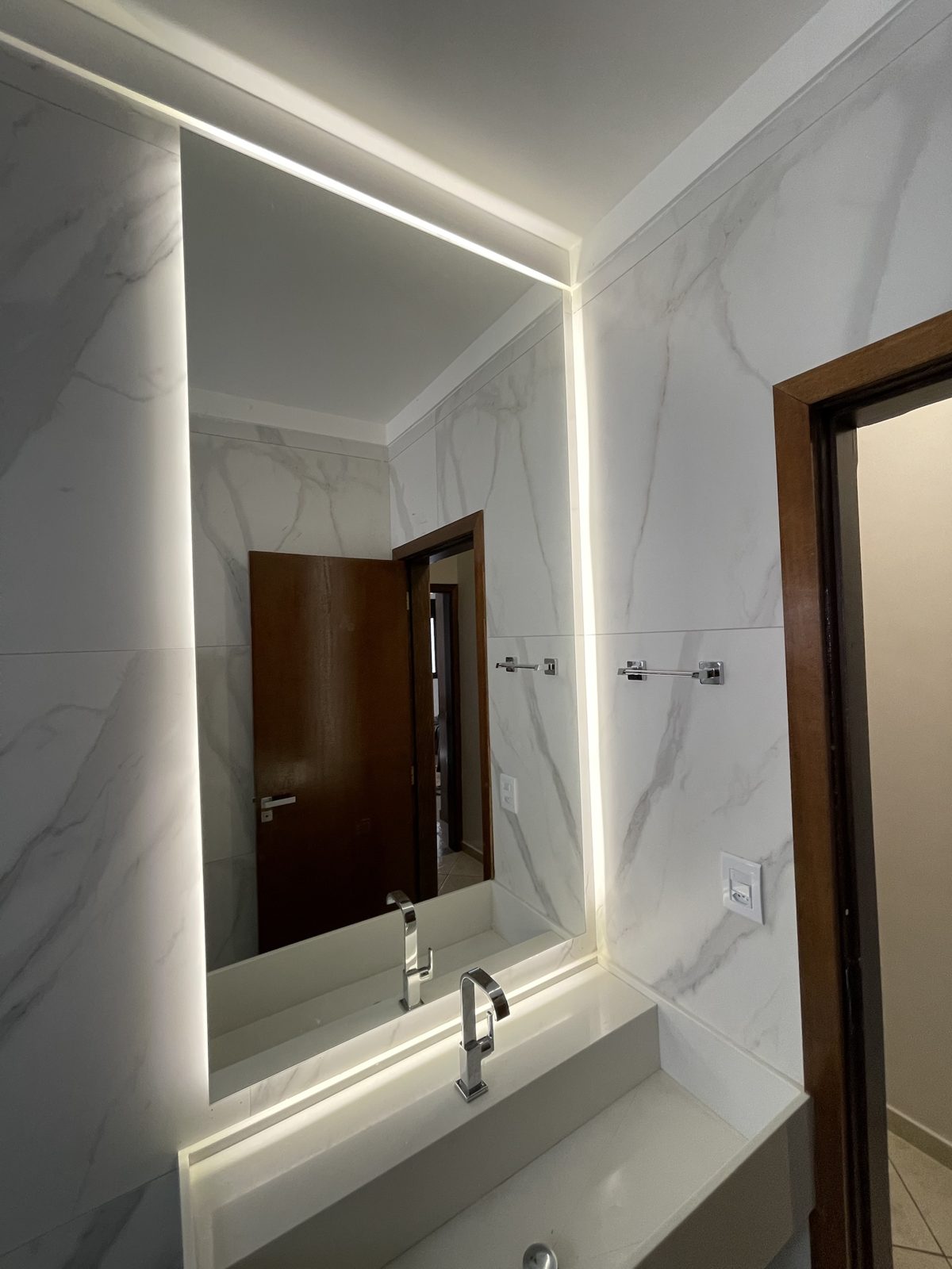 Espelho com iluminação de LED em banheiro com revestimento de mármore